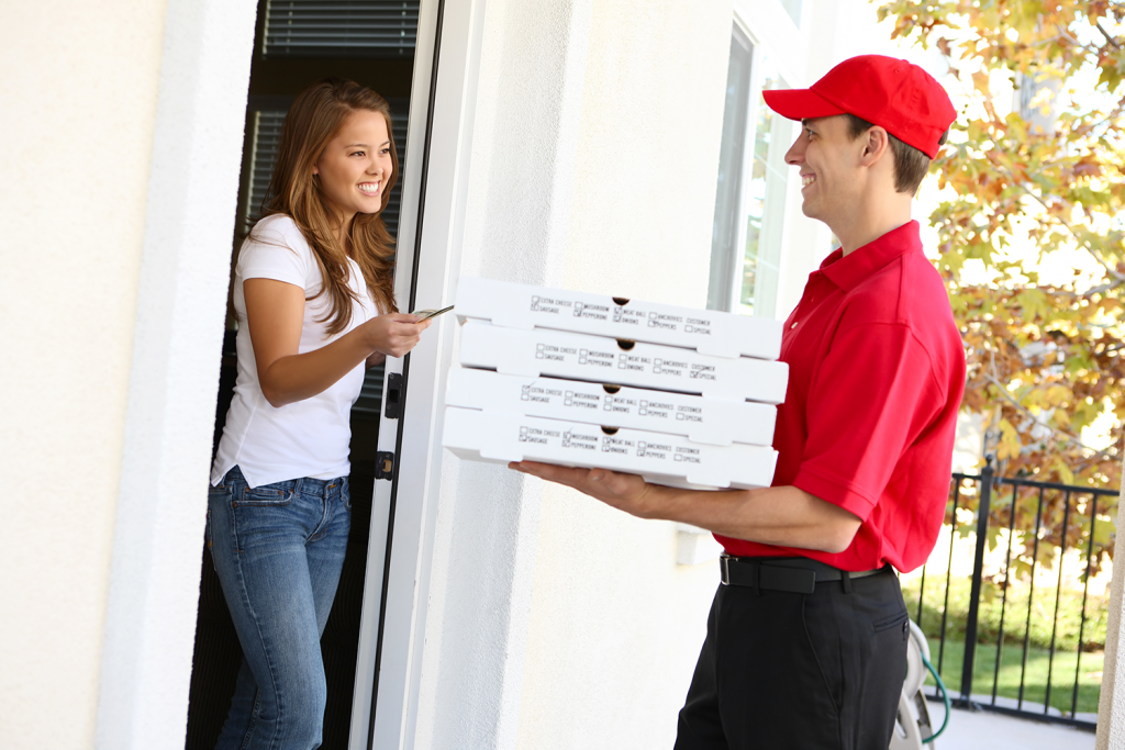 Pizza delivery guy handing three boxes to a guest at their home