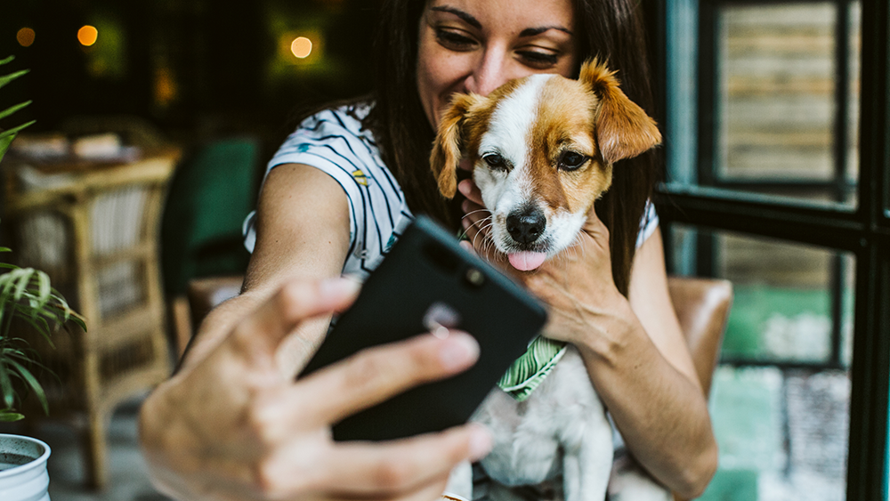 A woman takes a selfie with her dog at a pet-friendly restaurant/cafe
