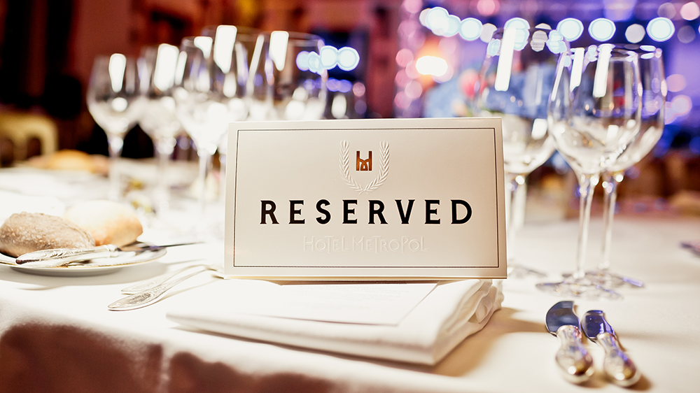 A reserved sign placard sits on a fabric napkin on a restaurant table ready for a party, like a wedding