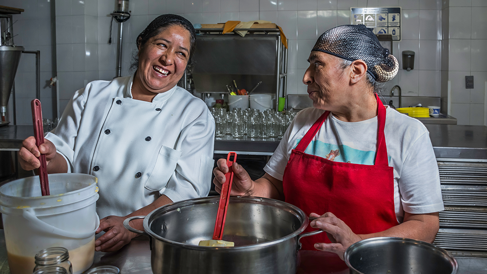 Two restaurant chefs smiling while they work.