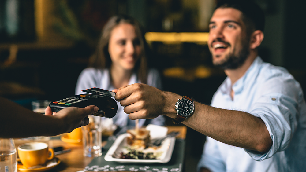 Two happy restaurant guests pay using mobile payment