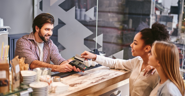 Two women pay for their meals at a restaurant.