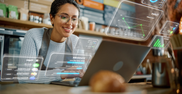 Restaurant worker looking at a laptop while futuristic UI overlays appear around her.