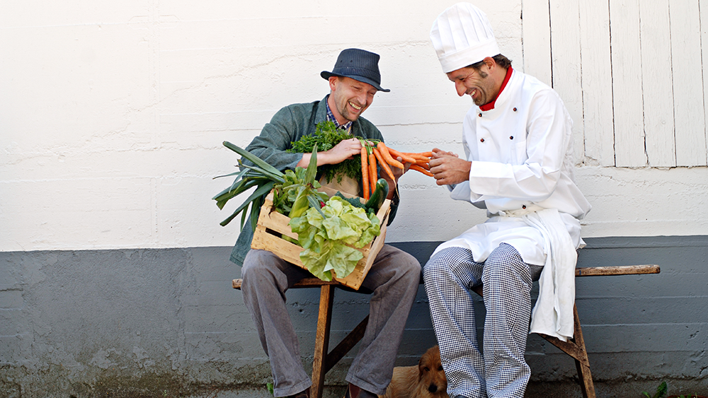 A local farmer shows off his produce to a restaurant chef.